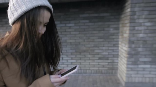 Young woman writing sms on smartphone while walk in city