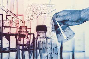 Researcher is dropping the reagent into test tube, with chemical equations background, in laboratory