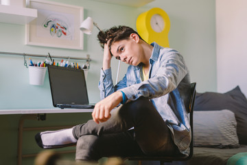 Teenage boy sitting in his room