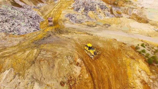 Aerial view of bulldozer on muddy construction site or dump. Heavy industry from above. Industrial background from devastated landscape.