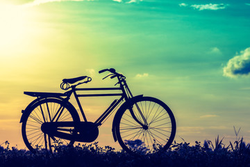 beautiful landscape image with Silhouette Bicycle at sunset vintage tone style