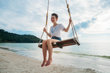 Happy girl on a swing tropical island