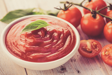 bowl of ketchup or tomato sauce and fresh tomatoes on wood table