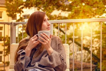 frau sitzt auf balkon terrasse und trinkt tee 
