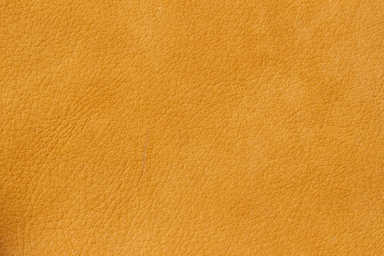 Texture of genuine leather close-up, cowhide. Sunny orange color. For natural, artisan backgrounds, substrate composition use, vintage design