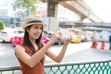 Woman taking photo on mobile phone in Bangkok