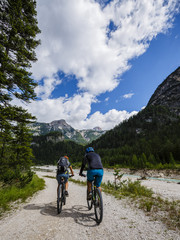 Fototapeta na wymiar Mountain biking couple with bikes on track, Cortina d'Ampezzo, Dolomites, Italy