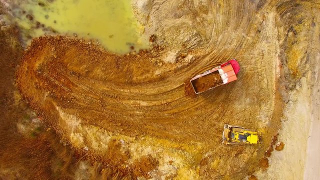 Aerial view of truck riding on muddy road trough a dump. Heavy industry from above. Industrial footage from devastated landscape. 