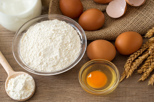 Eggs, flour and milk on wooden background.