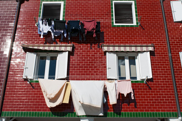 Scena all'aperto: un palazzo rosso e le finestre con il bucato steso ad asciugare