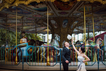 Fototapeta na wymiar Wedding day. Happy couple. Bride and groom in amusement park eating cotton candy