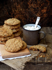 Flourless gluten free peanut butter, oatmeal, dried fruits cookies and cup of cocoa with marshmallows on wooden background. Vertical. Copy space
