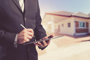 Business man working with a digital tablet on blurred home background ,loans concept.vintage process style