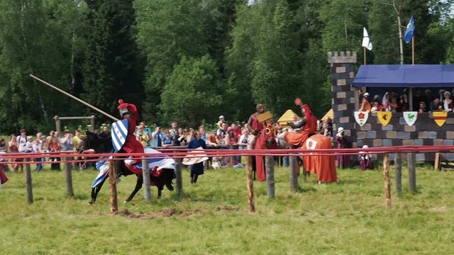 Medieval joust with knights on a hors in armour and costume. Battle with spear on stadium summer time.