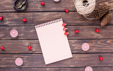 A blank notebook page, candles, vintage clock and cones on dark wooden background. Valentine's day. Flat lay.