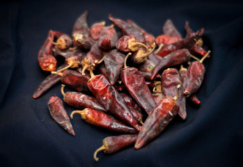 Dried red hot chili peppers are lying in a heap, glitering with different shades of red