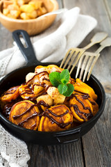 Small pumpkin pancakes with chocolate sauce in a pan on the old vintage wooden background. Selective focus.