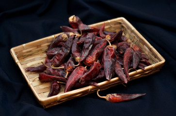 Dried red hot chili peppers are lying in a heap, glitering with different shades of red