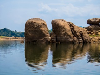 Rock formed island yellow stone reflection on water in Inginiyagala Senanayake Samudraya lake reservoir Sri Lanka	