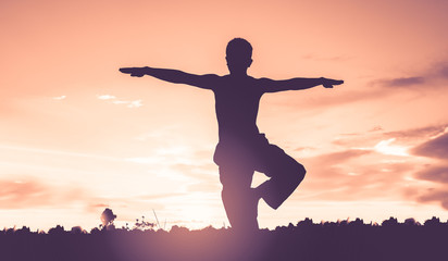 Silhouette of man practicing yoga with beautiful sunset