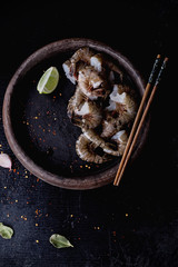 Raw Shrimps ready for cooking on the vintage ceramic plate with sesame seeds, lime, garlic and chili pepper flakes and lime leaf. Top View