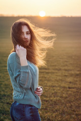 girl in a sweater is bathed in the rays of the evening sun