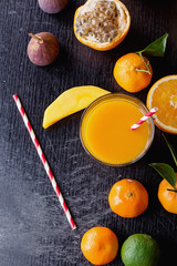 Variety of citrus tropical fruit with a glass of orange juice with a paper straw: Tangerines, grapefruit, lime, oranges and banana. Top View. Copy Space