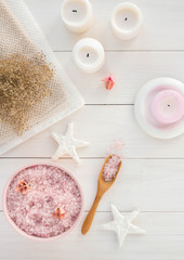 Spa composition with candles, sea salt and flowers on white wooden background. Flat lay.