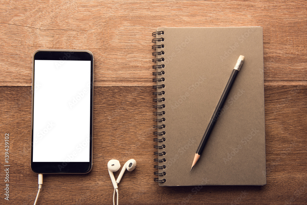 Aufkleber Smartphone with white screen and Note book On Wooden Table With Copyspace