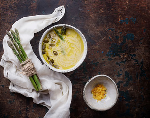 Freshly made asparagus soup served with asparagus stalks, saffron salt an extra virgin olive oil on rustic wooden board. Top View
