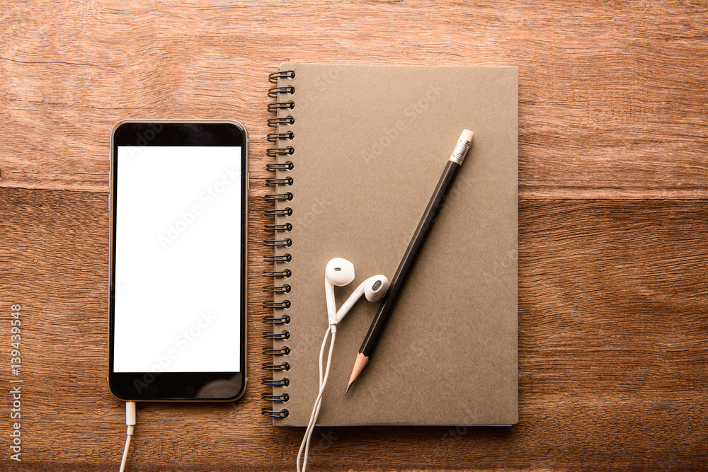 Aufkleber Smartphone with white screen and Note book On Wooden Table With Copyspace