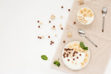 Healthy breakfast with yogurt, muesli and banana on white background. Flat lay