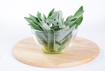 Sage leaves  in glass bowl on round wooden cutting board