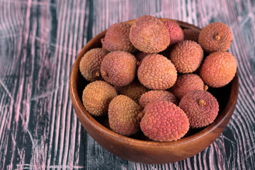 Lychee in a wooden bowl on a wooden background