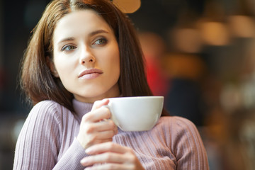 Beautiful young woman with a cup of tea at a cafe