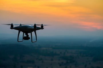 Fototapeta na wymiar Silhouette of Quad copter flying on a mountain view at beautiful twilight sky. drone, aerial Vehicle at sundown and copy space.