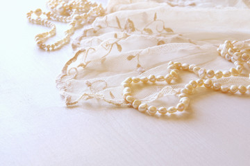 Background of white delicate lace fabric and pearls.