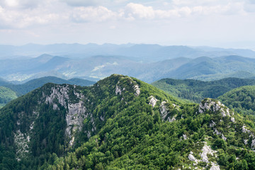 Fototapeta na wymiar Panoramic view from the top of mountain to many mountain peaks around in Risnjak National Park in Croatia. Magnificent mountain ridge on foreground.