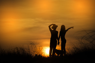 Silhouette of couple standing on the beach with sunset background.Woman pointing something.