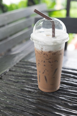 Ice coffee in plastic cup on the wooden table