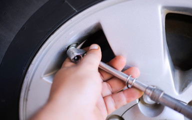 Closeup Of Mechanic At Repair Service Station Checking Tyre Pressure With Gauge inflating the automobile wheels via a pump