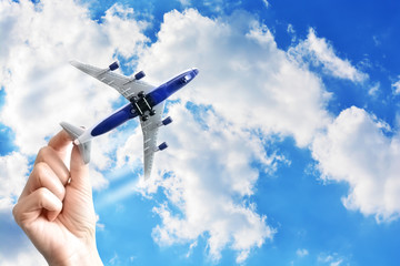 Hand holding a toy plane against blue sky