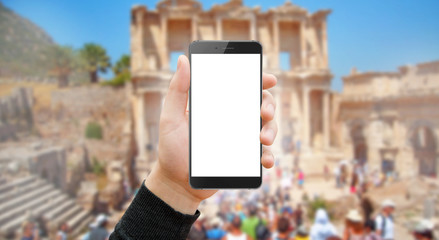 Man holding modern black phone with empty screen in hand. Blurred antique city and old buildings in background