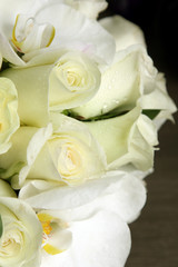 beautiful white and yellow wedding bouquet of roses and orchids on dark background