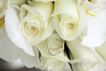 background of beautiful wedding bouquet of roses and orchids and two gold and platinum wedding rings