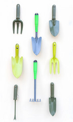 Gardening tools shovel, rake hanging on white wood background.