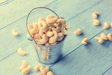 raw cashew nuts in bucket on blue wood table