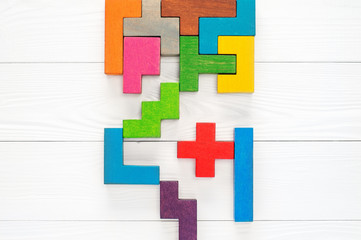 Obraz premium Concept of creative, logical thinking. Different colorful shapes wooden blocks on white wooden background, flat lay, copy space. Geometric shapes in different colors, top view. Abstract Background.