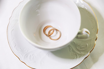 Obraz na płótnie Canvas Два золотых кольца на в белой чашке и белом блюдце