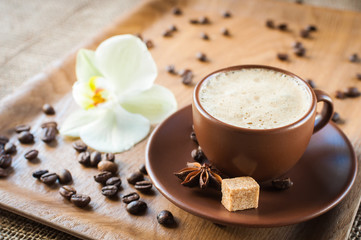 cup of coffee on wooden background decorated with spices and flower